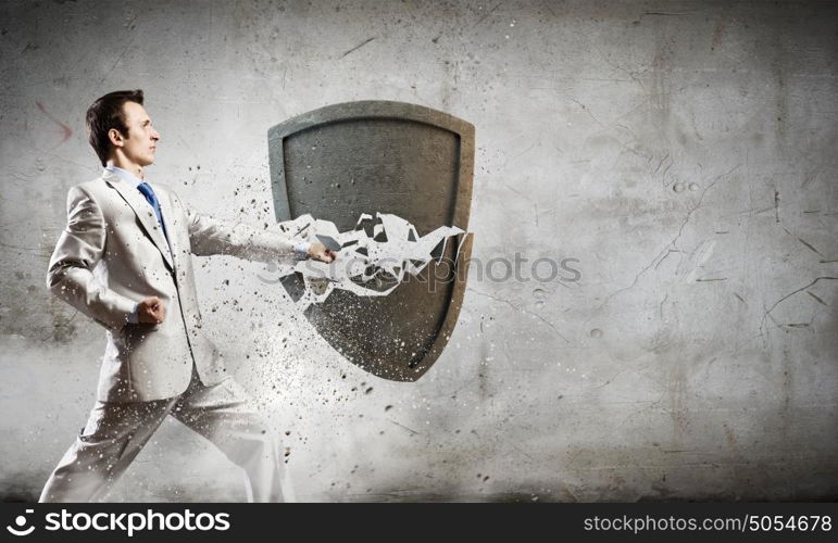 Security concept. Businessman breaking stone shield with karate punch