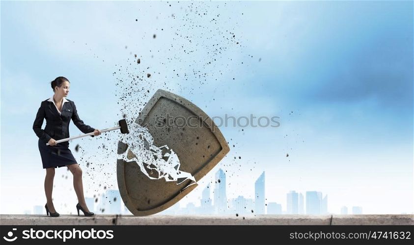 Security concept. Young businesswoman crashing stone shield with hammer