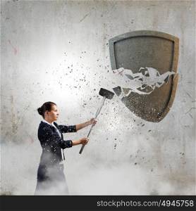 Security concept. Young businesswoman crashing stone shield with hammer