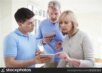Security Consultant Demonstrating Alarm System To Mature Couple