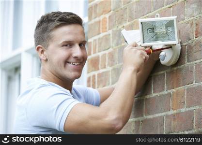 Security Consultant Fitting Security Light To House Wall