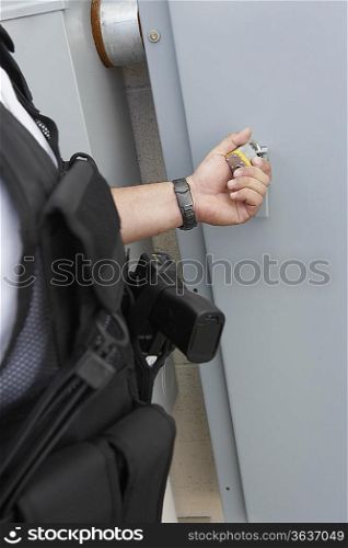 Security guard checking padlock, mid section