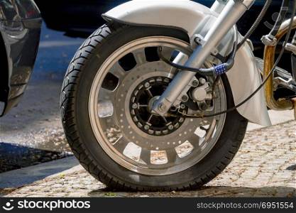Security number padlock blocking motorcycle wheel on the street.