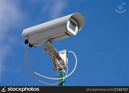 security video camera on background blue sky