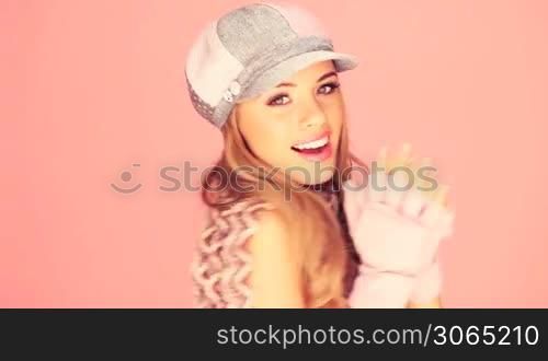 Seductive Blond In Winter Outfit with beautiful smile facing out of frame with copyspace on pink.