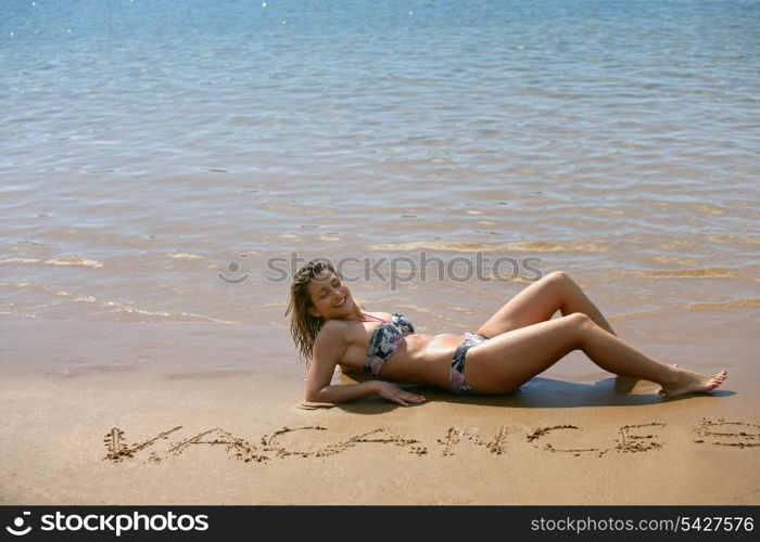 Seductive blond laying on the beach in bikini