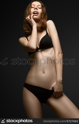 Seductive woman in black underwear on black background