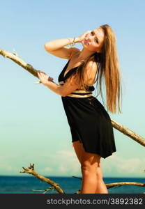 Seductive woman outdoor in summer. Sexual young model in black dress on beach.