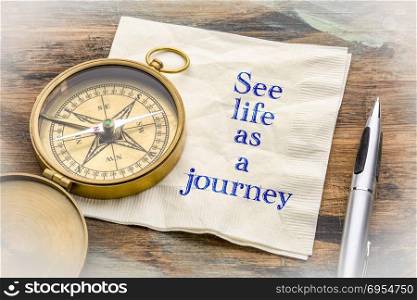 See life as a journey - inspiraitonal handwriting on a napkin with an antique brass compass