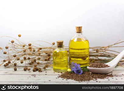 Seed flowers and flax oil bottles on white wood. bottles of linseed oil flowers and seeds