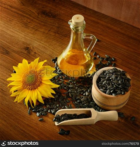 Seeds, oil and sunflower flower on a wooden background