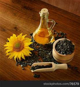 Seeds, oil and sunflower flower on a wooden background