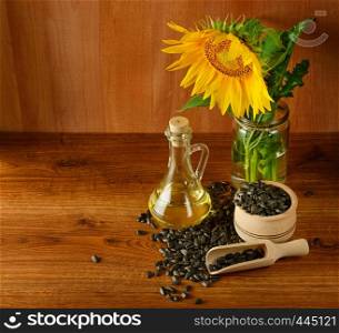 Seeds, oil and sunflowers flower on a wooden background.