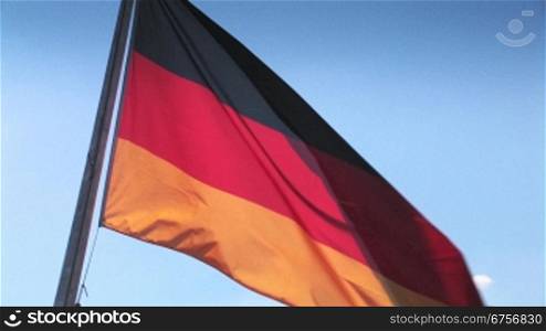 Sehr sch?ne Deutschlandflagge mit ihren leuchtenden Farben weht sanft und gleichmSssig im Wind vor hellblauen himmel
