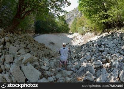 seinor male hiker relaxing in nature while  walking tour on beautiful summer day on canyon of  dried riverbed