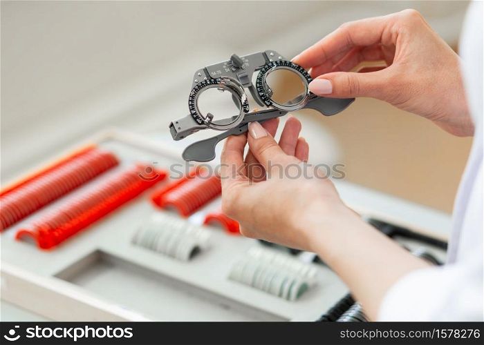 Selecting size. Ophthalmologist in white robe holding unusual glasses for measuring eyesight for lenses. Ophthalmologist in white robe holding unusual glasses for measuring