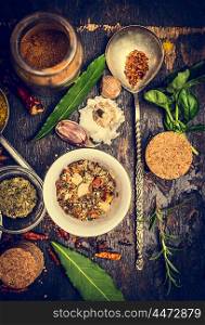 selection of colorful herbs and spices in spoon and bowl on rustic wooden background, top view, toned
