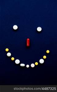 Selection of tablets in the shape of a smiley face on black background