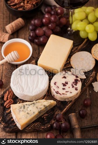 Selection of various cheese on the board and grapes on wooden table background. Blue Stilton, Red Leicester and Brie Cheese.