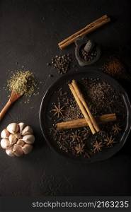 Selection of various spices on textured black background. Pepper, cardamom, clove, garlic, cinnamon, star anis, dehydrated parsley.Flat lay