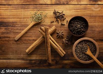 Selection of various spices on wooden rustic board background. Pepper, cardamom, clove, cinnamon, star anis, dehydrated parsley.Flat lay