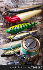 selectiv focus top closeup fishing bait wobbler and reel with line on birch wooden background