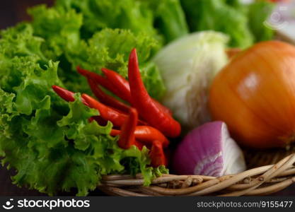 Selective focus and close up with green lettuce leaf and Ingredient herb for cooking salad in wicker basket on wooden table, copy space for insert text