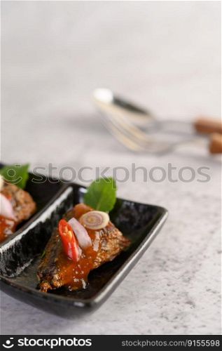 Selective focus appetizers with the spicy sardine in ceramic tray, spoon and fork in blurred background, copy space