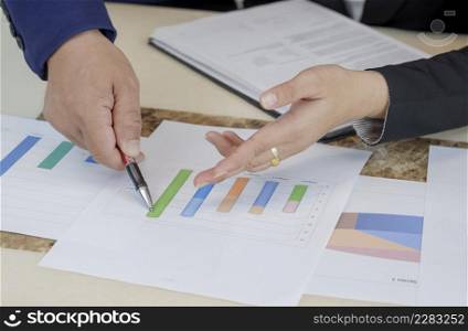Selective focus at hands of business woman and supervisor are pointing graph chart during analyze the company's sales plan in office room