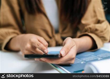 Selective focus, Close up finger of Young woman use smartphone while working on laptop and paperwork or report presenting Project growth graph at cafe
