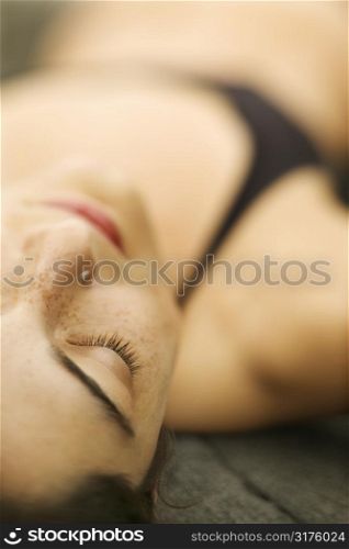 Selective focus close up of Caucasian young woman lying on rock.