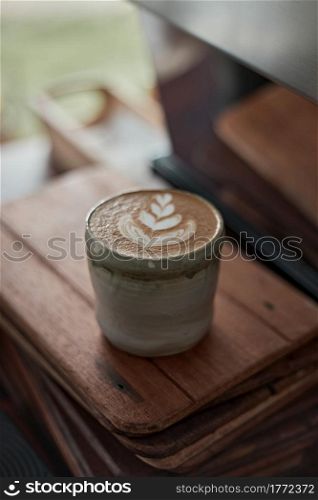 Selective focus cup of hot latte art coffee on wooden table,focus at white foam. hot latte art coffee