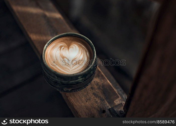 Selective focus cup of hot latte art coffee on wooden table,focus at white foam. up of hot latte art coffee on wooden 