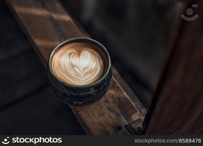 Selective focus cup of hot latte art coffee on wooden table,focus at white foam. up of hot latte art coffee on wooden 