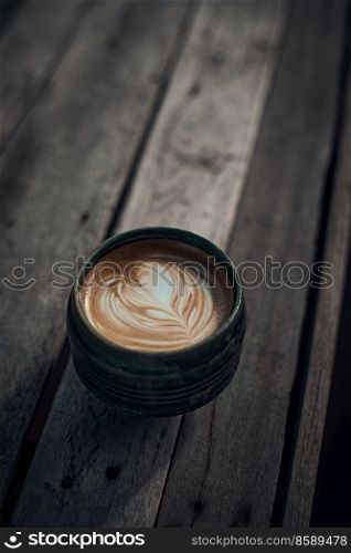 Selective focus cup of hot latte art coffee on wooden table,focus at white foam. up of hot latte art coffee on wooden 