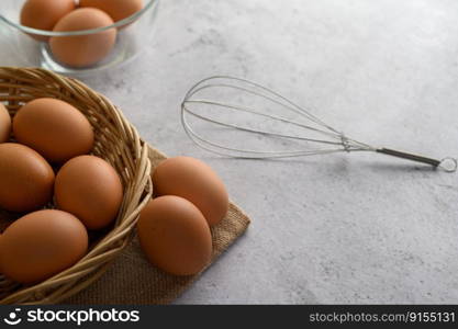 Selective focus eggs on sack cloth, many eggs on wicker basket and glasses bowl, the egg whisk placed on the floor, copy space