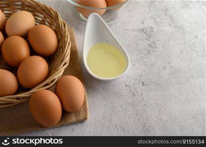 Selective focus eggs on sack cloth, many eggs on wicker basket and oil in bowl placed on the floor, preparing for cooking food or dessert, copy space