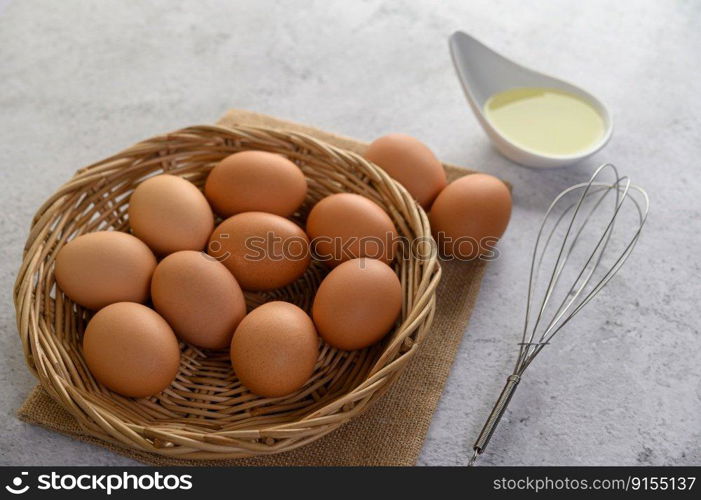 Selective focus eggs on sack cloth, many eggs on wicker basket and glasses bowl, oil and egg whisk placed on the floor, preparing for cooking food or dessert, copy  space