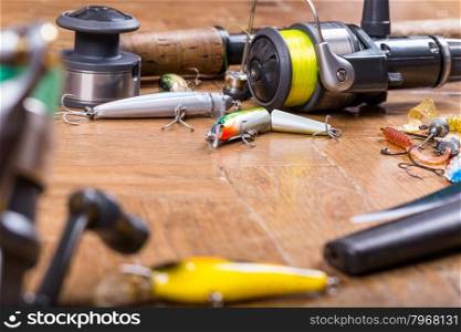 selective focus fishing baits wobbler, rod, knife and reel with line on wooden background