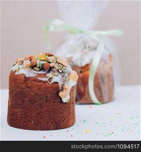 Selective focus freshly baked Easter cake with icing, nuts, seeds, candied fruit, multicolored sweet sprinkles against white backdrop. Easter, birthday greeting card or web banner concept. Square image