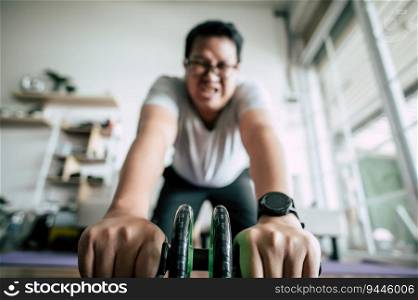 Selective focus, Funny overweight man wearing eyeglasses is workout with ABS hand-roller for healthy, copy space