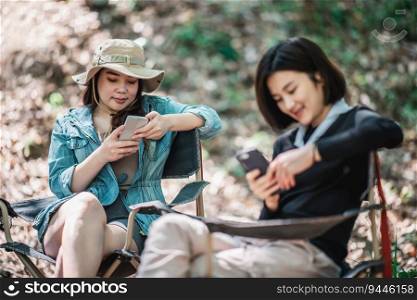 Selective focus, Group of girl friends sitting on c&ing chair and use their smartphone ignoring each other while c&ing in park