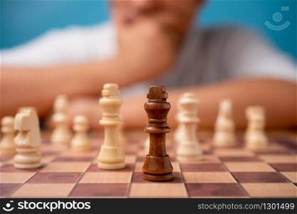 Selective focus of brown king chess and background of businessman thinking strategy and competitor evaluation in competition. Concept of leadership, business strategy.