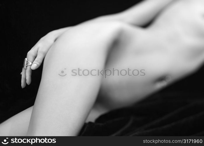 Selective focus of Caucasian mid adult female nude body lying on side.