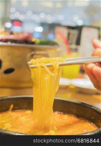 Selective focus of chopstick with noodle ready to be eaten
