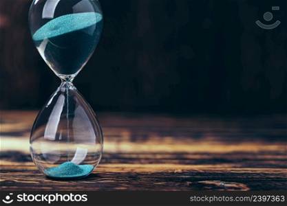 Selective focus of hourglass with green sand on wooden background. hourglass with green sand