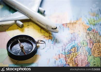 selective focus of miniature tourist on compass over map with plastic toy airplane,abstract background to travel concept.
