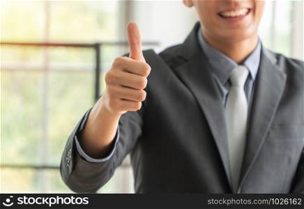 Selective focus of thumbs. Young businessman showing thumbs up to successful business. Concept of new Entrepreneurial success in business startup.