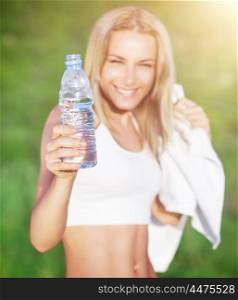 Selective focus on a woman holding bottle of water, doing sport exercise outdoors, healthy nutrition, enjoying fitness life&#xA;