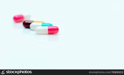 Selective focus on antibiotic capsule pill. Pharmaceutical industry. Prescription drugs. Pharmacy web banner. Pink, blue, yellow, red capsules pill on white background. Antibiotic drug resistance.